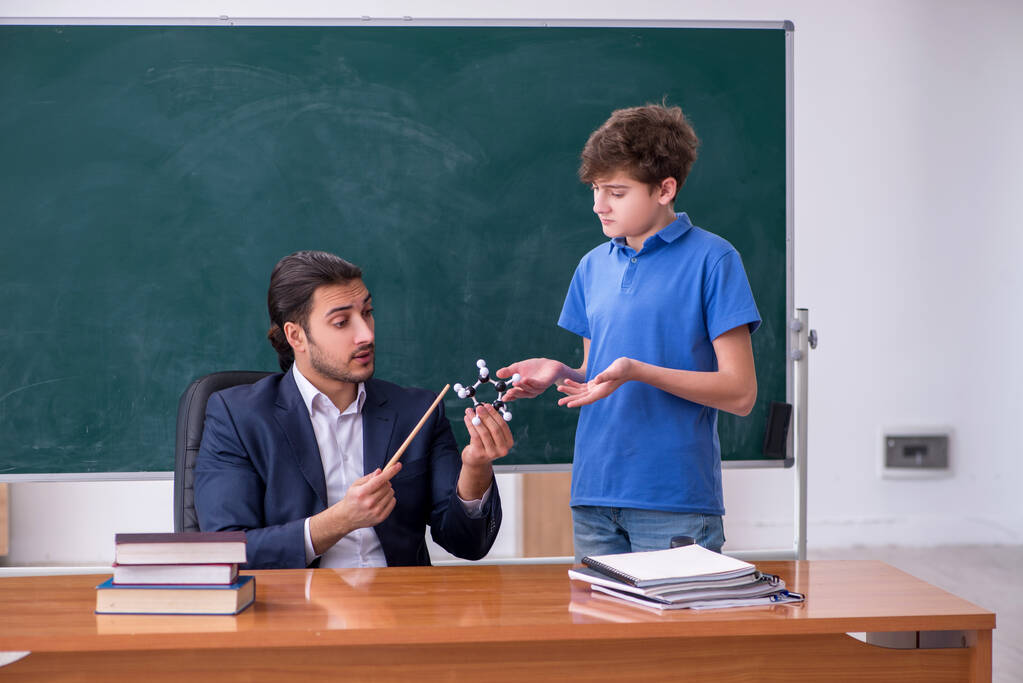 young male teacher and schoolboy in the classroom